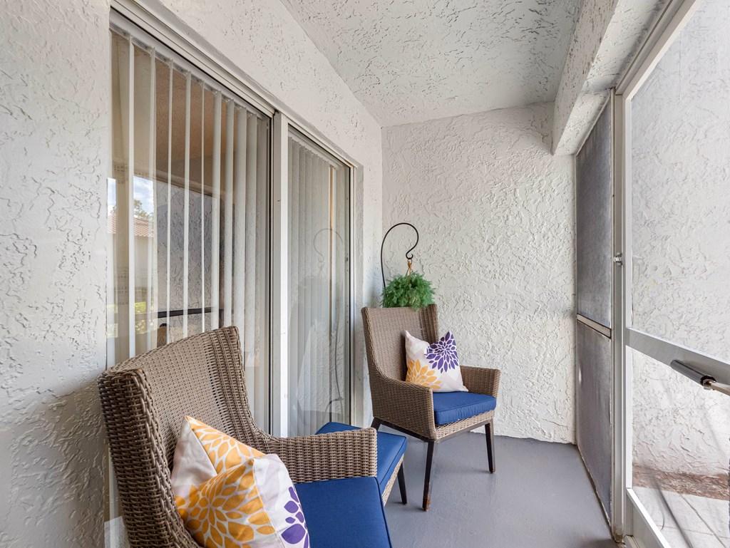 A chair with a blue cushion sits in a room with a window.